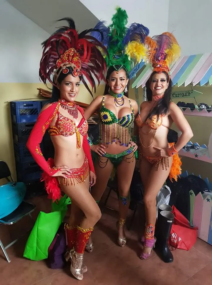 Tres bailarinas de batucada con trajes de samba de colores